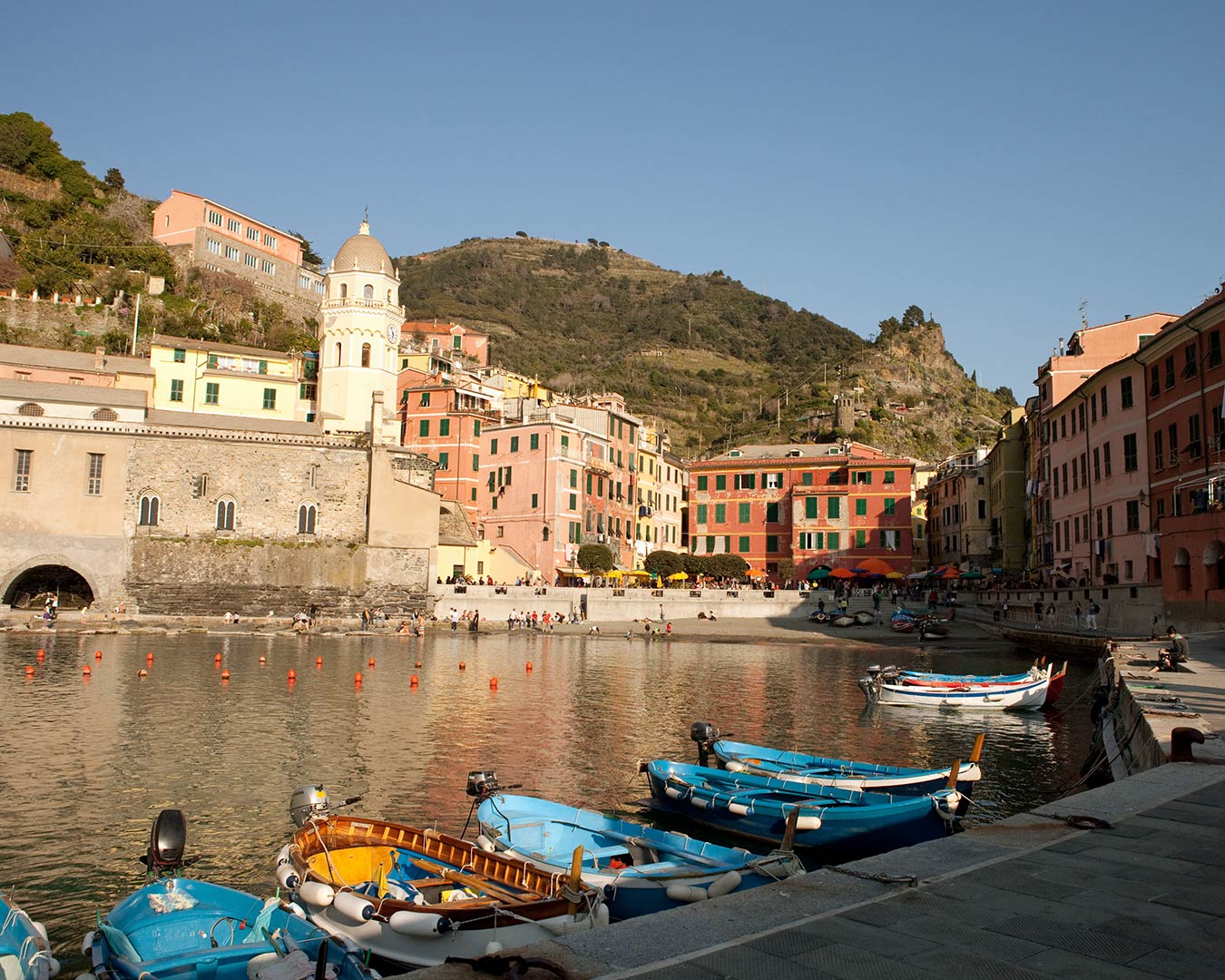 Harbor view: colorful buildings, boats, water, and a mountain in Vernazza, Italy.