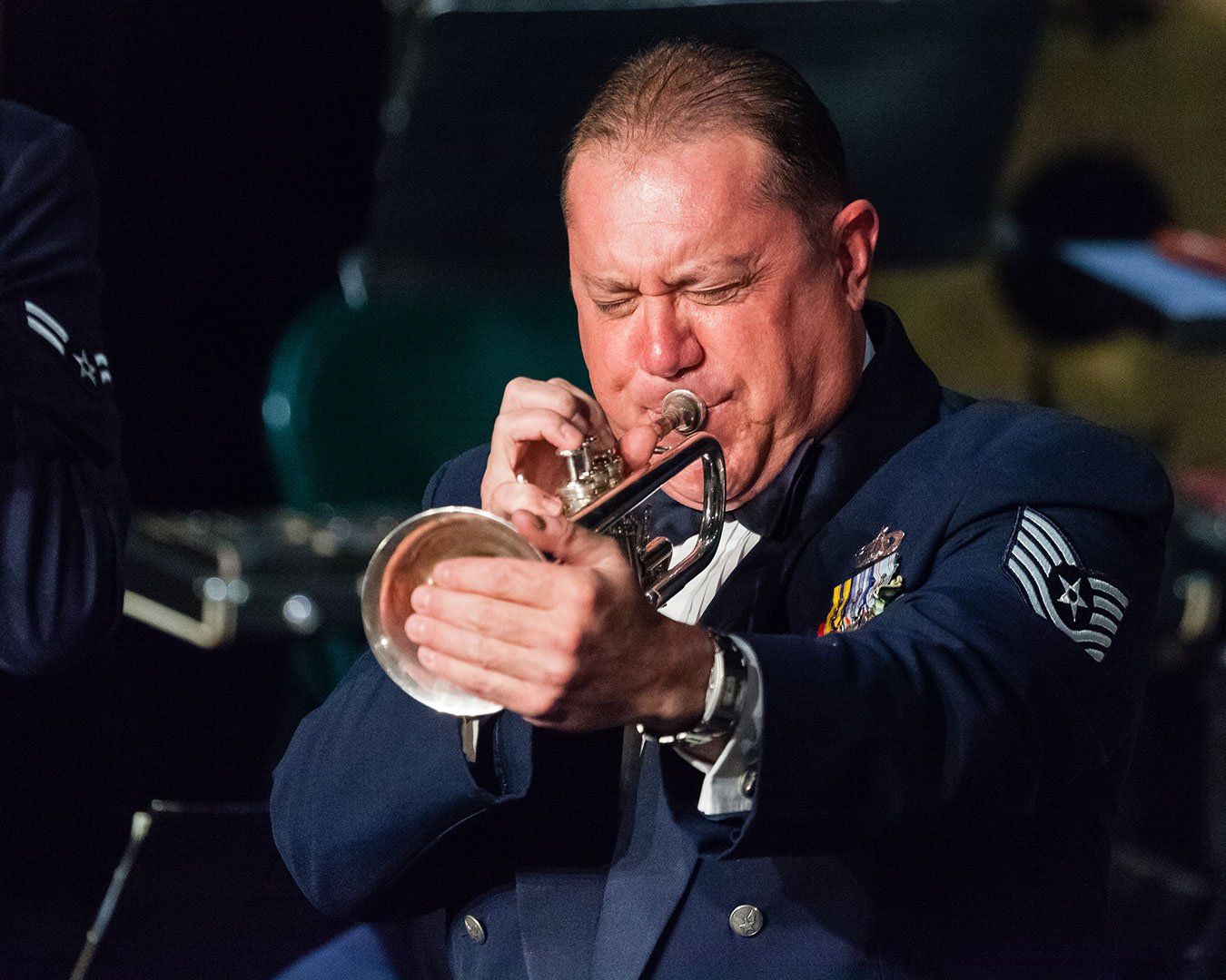 Trumpet player in Air Force uniform performing with focused expression.