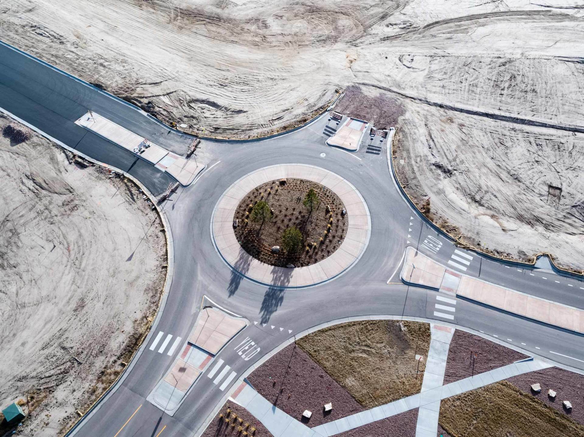 Aerial view of a roundabout under construction, surrounded by unfinished roads and landscaping.