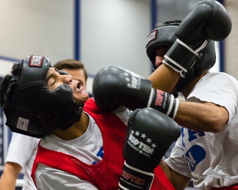 Two boxers in headgear sparring; one is struck in the face.