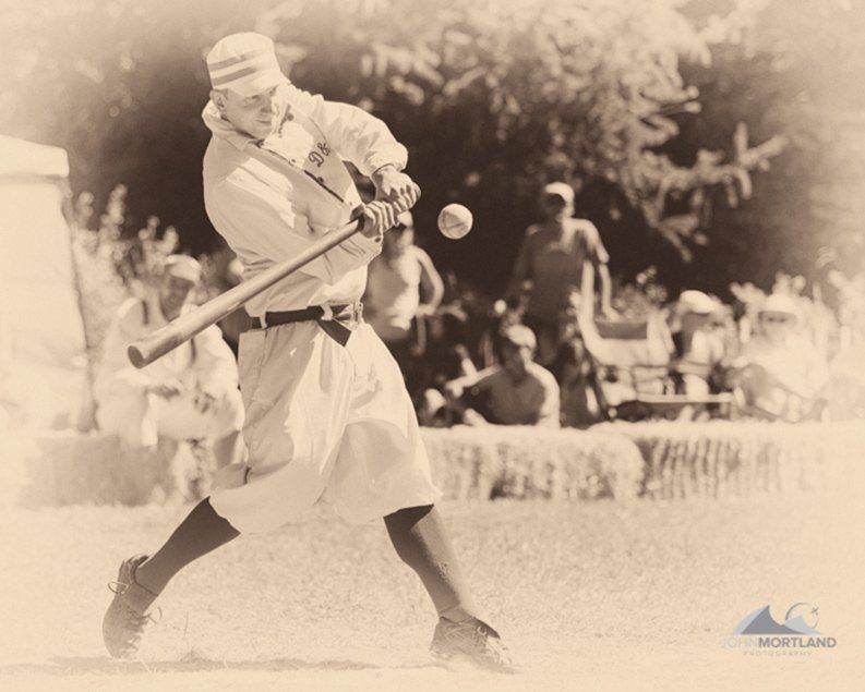 Batter swings at a baseball during a game. Vintage photo, outdoors.