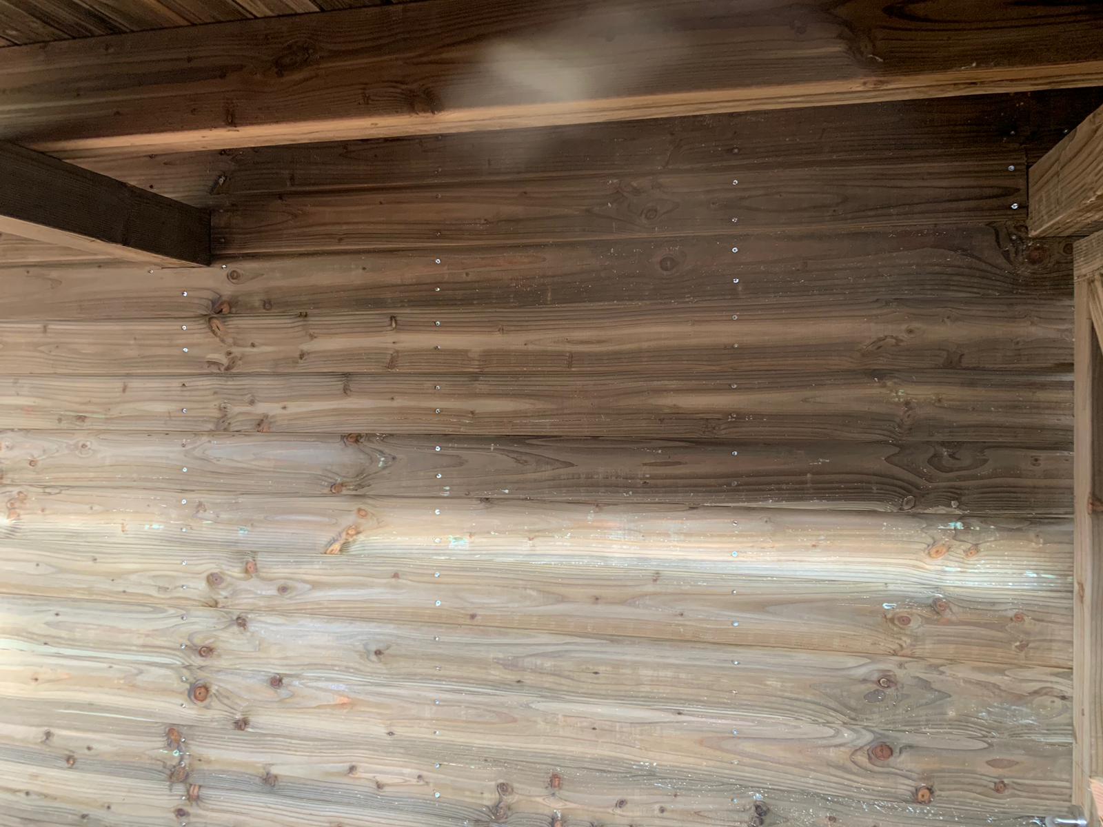 Interieur van een verweerde houten constructie met stofdeeltjes, verlicht door licht. Een lichtstraal schijnt door de ruimte.