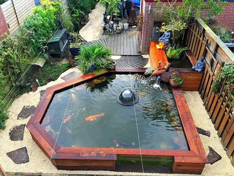 Bovenaanzicht van een kleine vijver in een achtertuin met koi, houten randen en een fontein, omgeven door beplanting.