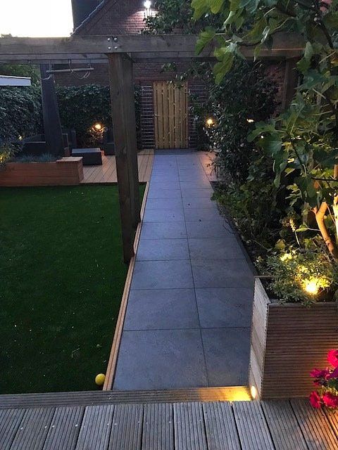 Tuinpad in de achtertuin leidt naar een schuur met een pergola en een gazon.