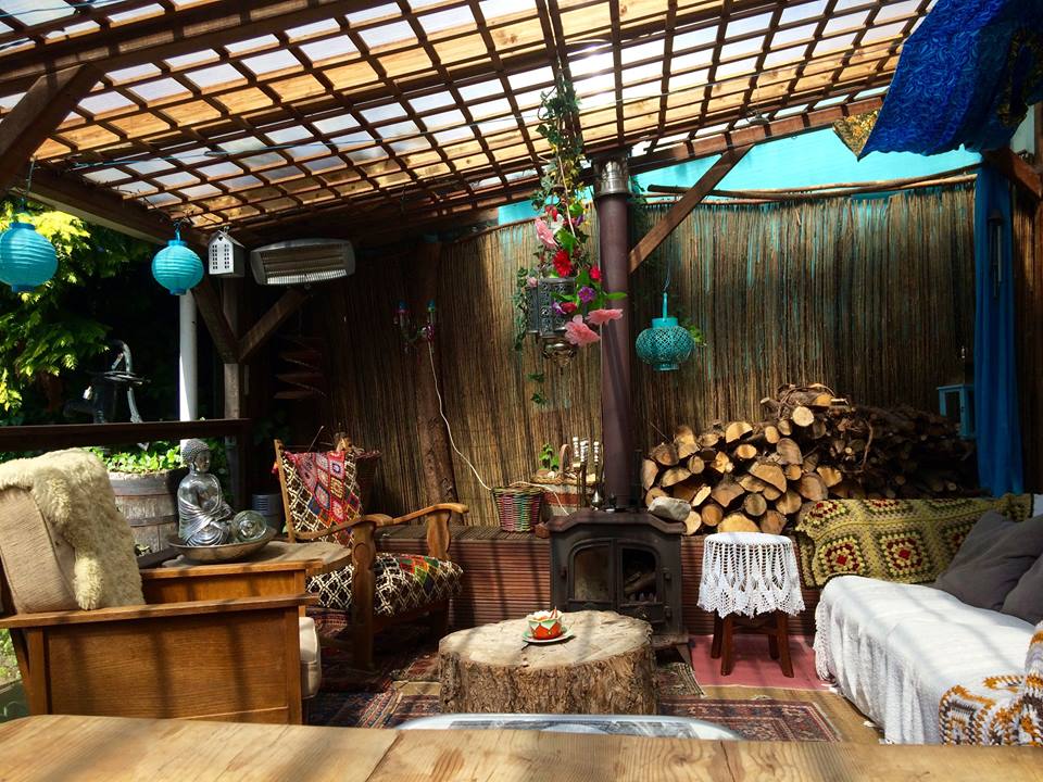 Gezellige buitenruimte met rustieke inrichting, houten pergola en houtkachel.