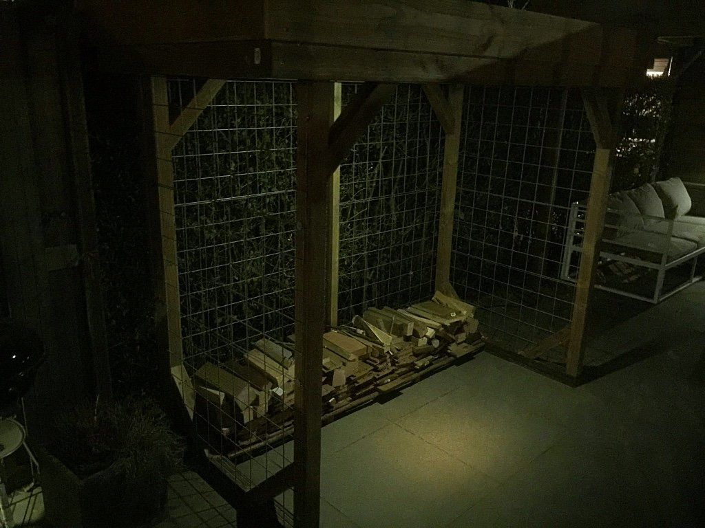 Houten wijnrek gevuld met flessen, met zitplaatsen op de achtergrond.