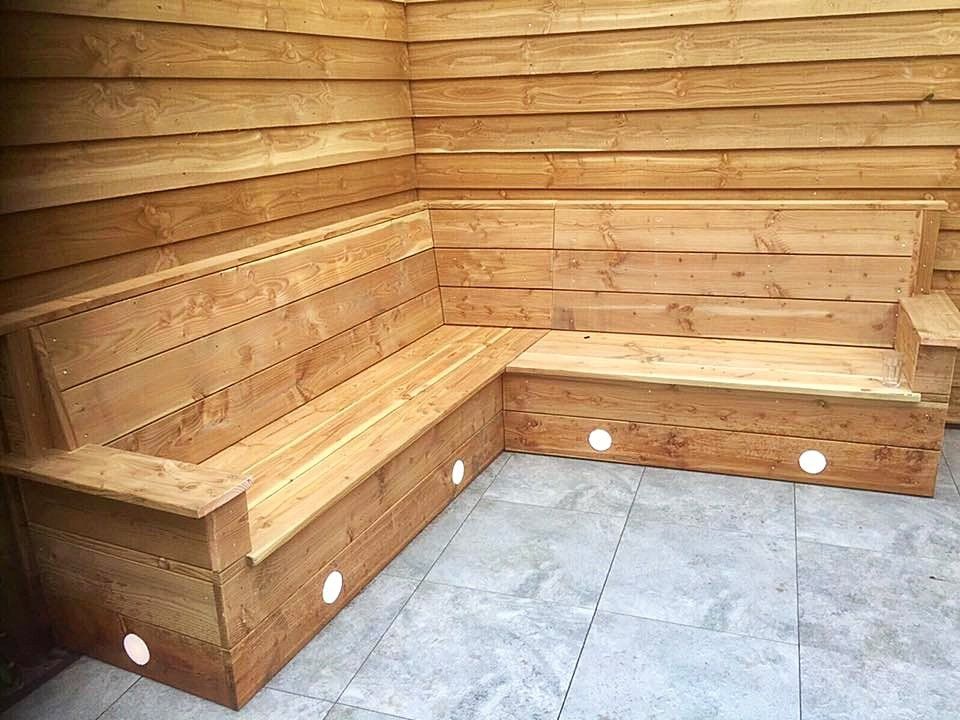 Houten hoekbank met ingebouwde verlichting, geplaatst in een met houten panelen beklede ruimte op een tegelvloer.