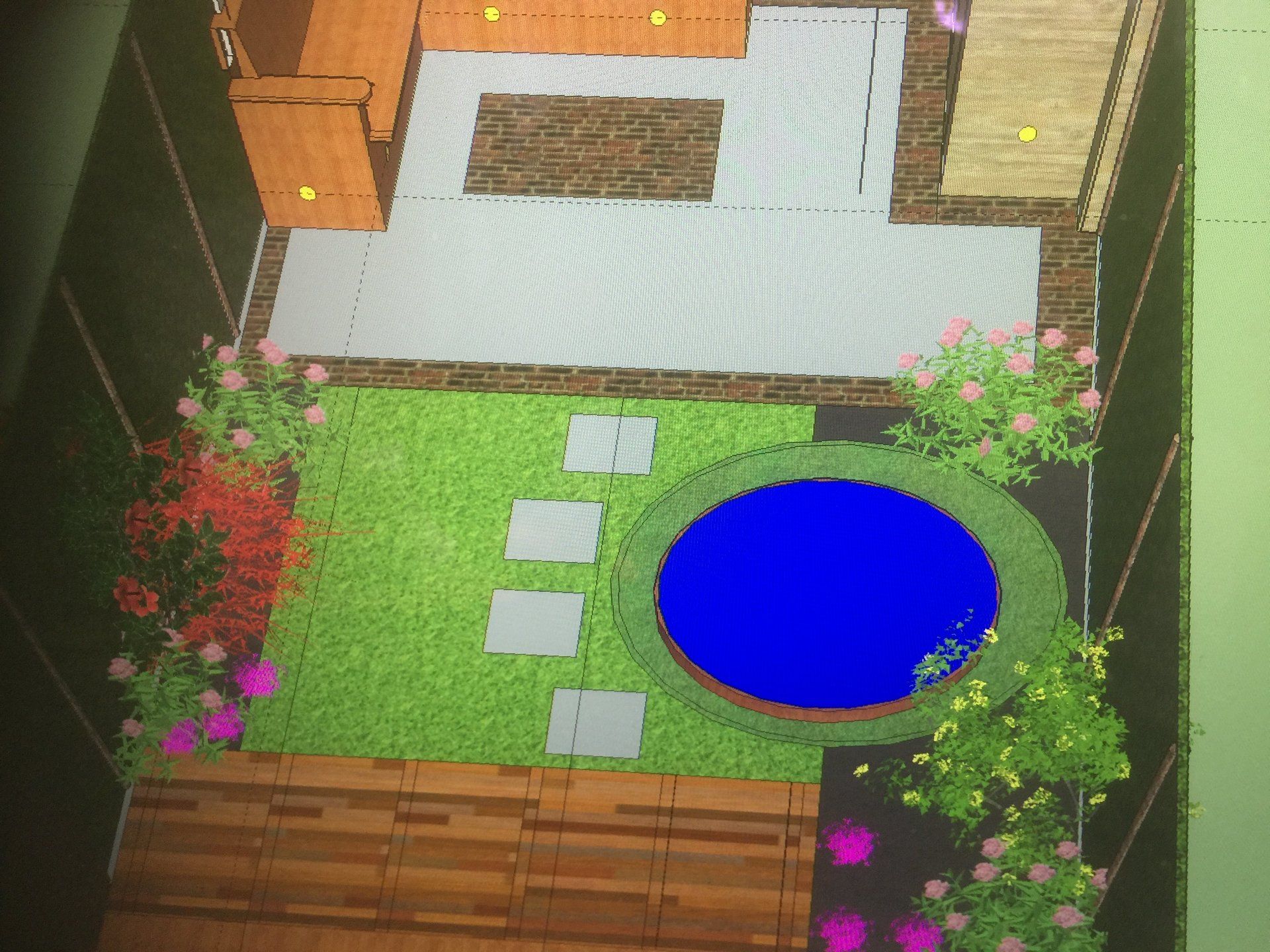 Bovenaanzicht van een tuinplan met een zwembad, terrasmeubilair en aangelegde beplanting, met groen gras, een blauw zwembad en bloemperken.