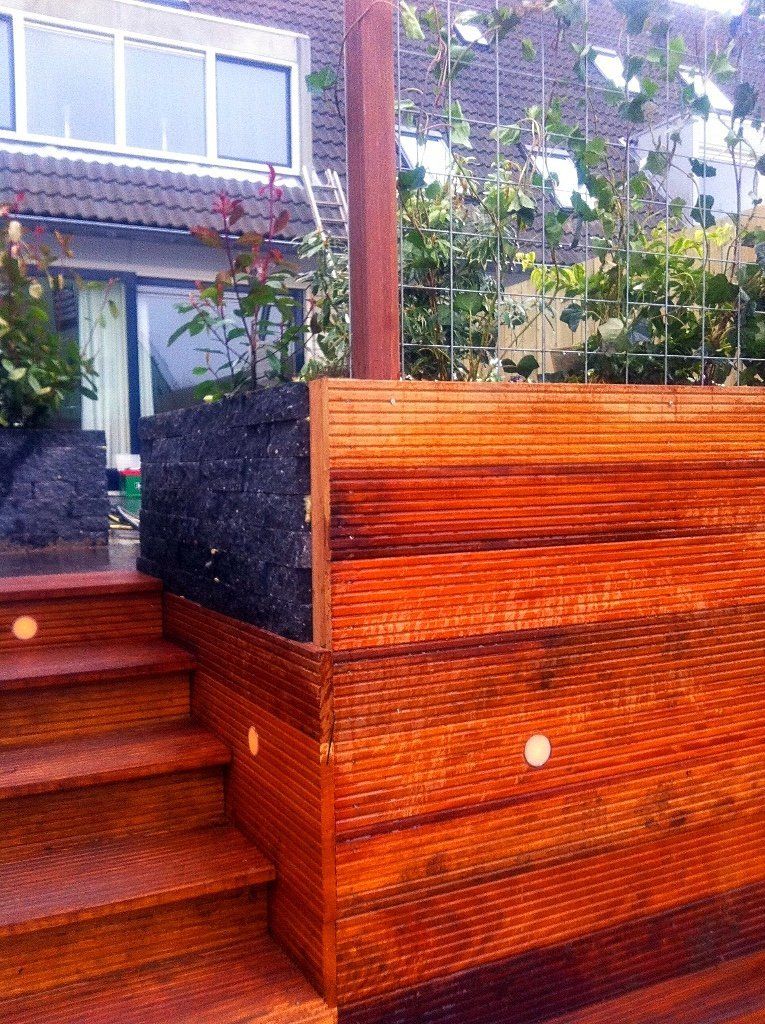 Houten terras met trap, ingebouwde verlichting en een verticale tuin.