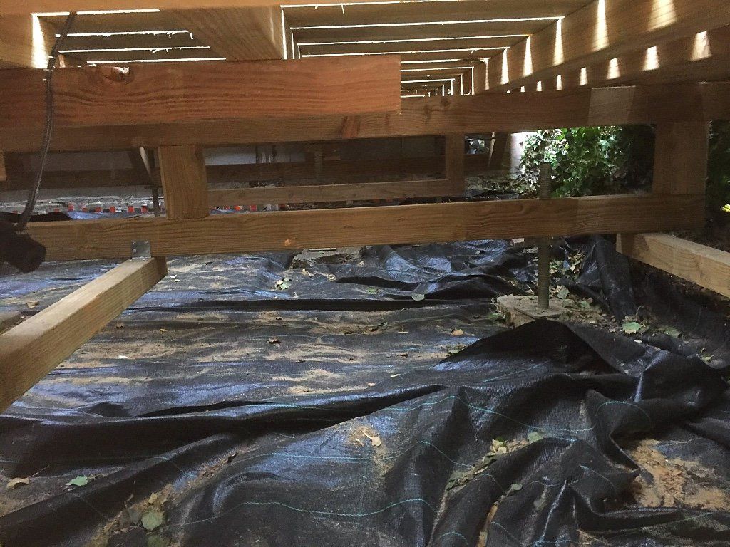 Onder een houten terras met een donkere stoffen bodembedekking.