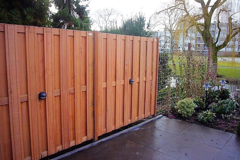 Houten privacyscherm met twee handgrepen op een terras.