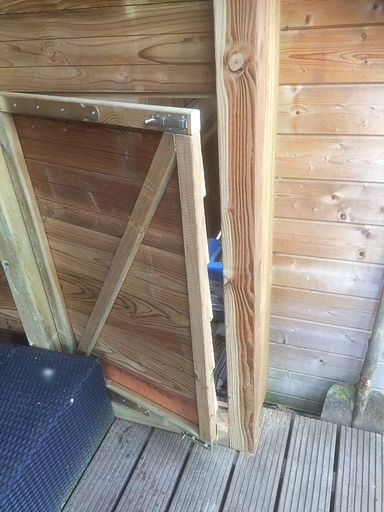 Houten schuttingpanelen leunen tegen een houten paal en muur.