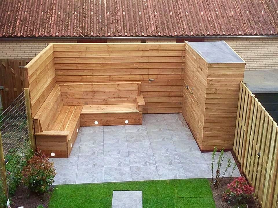 Houten zitgedeelte buiten met grijze tegelvloer en groen gazon.