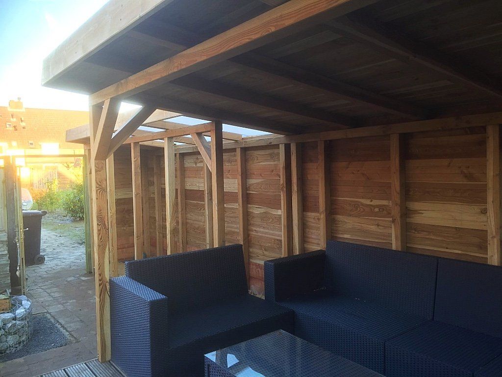 Houten buitenruimte met donkerblauwe zitmeubels en tafel.