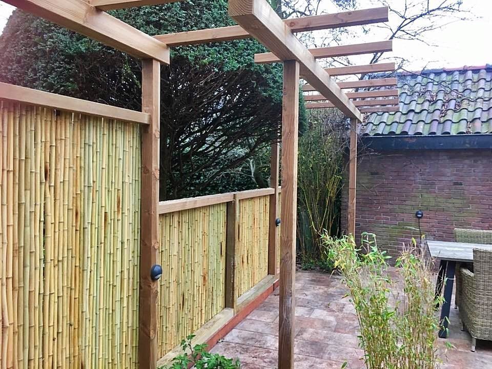 Bamboe schutting en houten pergola in een achtertuin.
