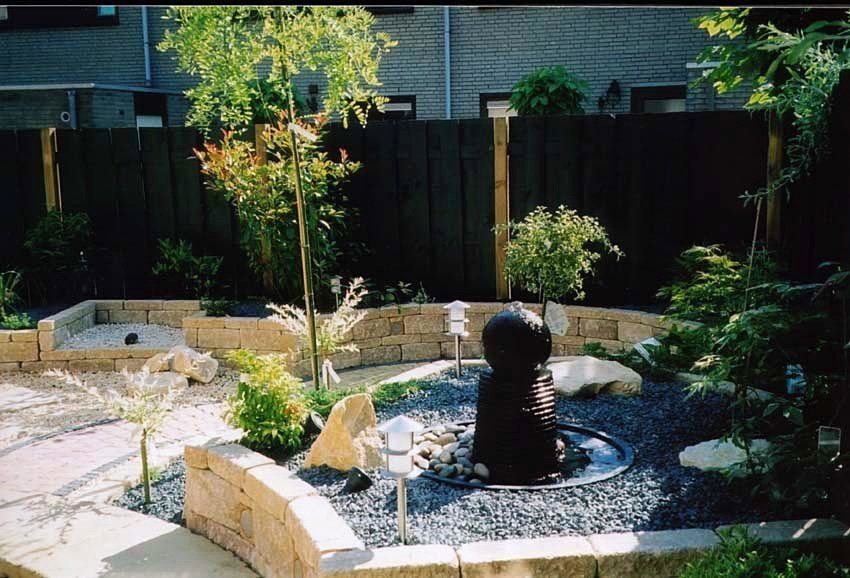 Zen-tuin met een donkere waterfontein, grind, stenen en gebogen stenen muren.