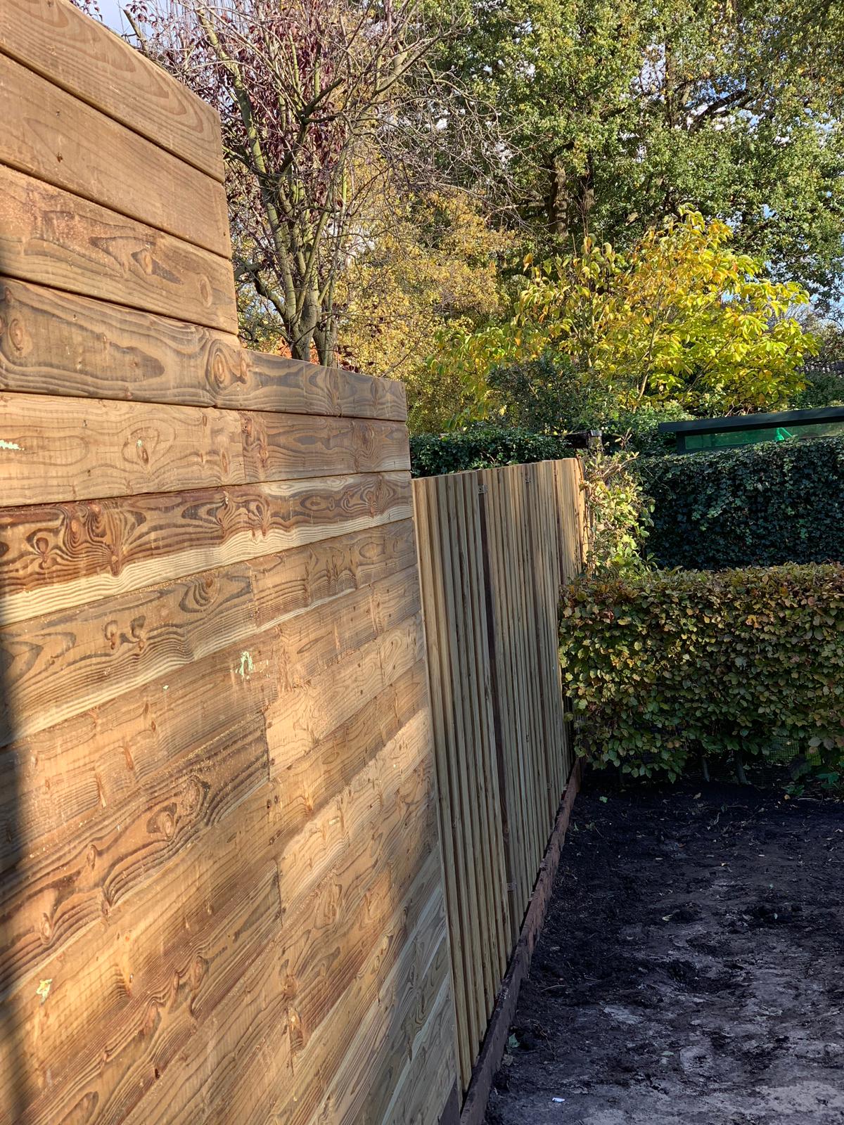 Houten schutting in een zonnige buitenomgeving met bomen en groen op de achtergrond.