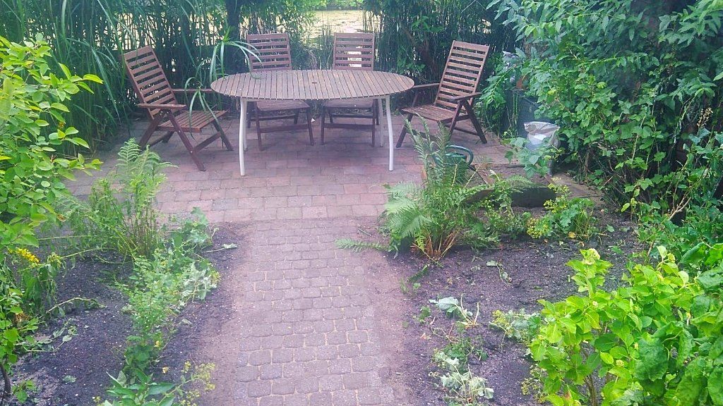 Houten terras op een stenen terras, omgeven door groen.
