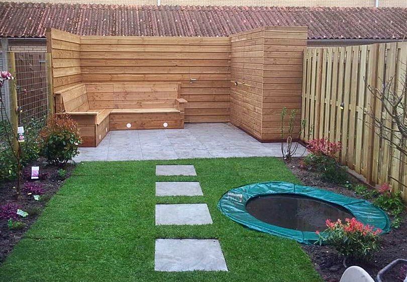 Houten zithoek in een achtertuin met een graspad, trampoline en houten schutting.
