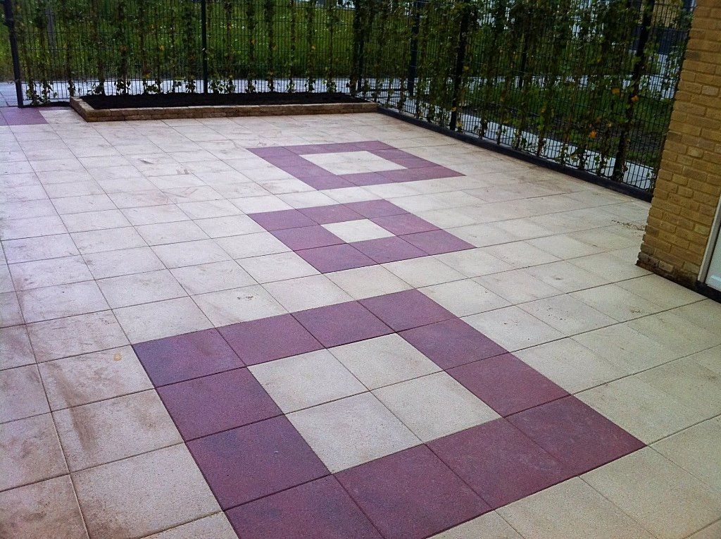 Terras met rode vierkante tegels, omzoomd door een zwarte balustrade en beplanting.