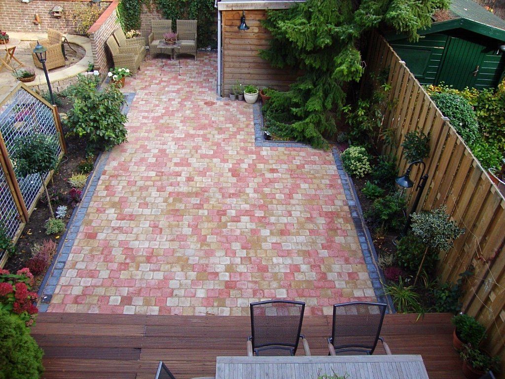 Bakstenen terras met tuin, houten vlonder, schuur en zitgedeelte.