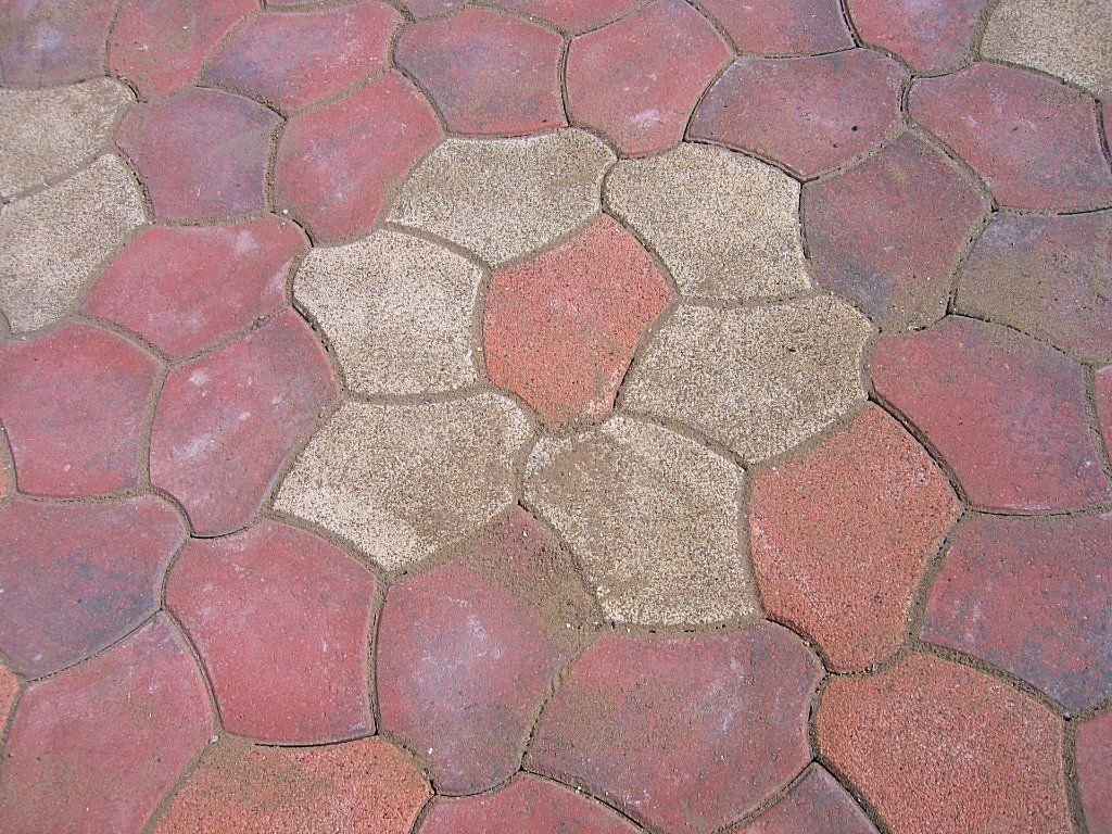 Close-up van een straat met kasseien, bestaande uit een mix van rode, beige en grijze stenen.