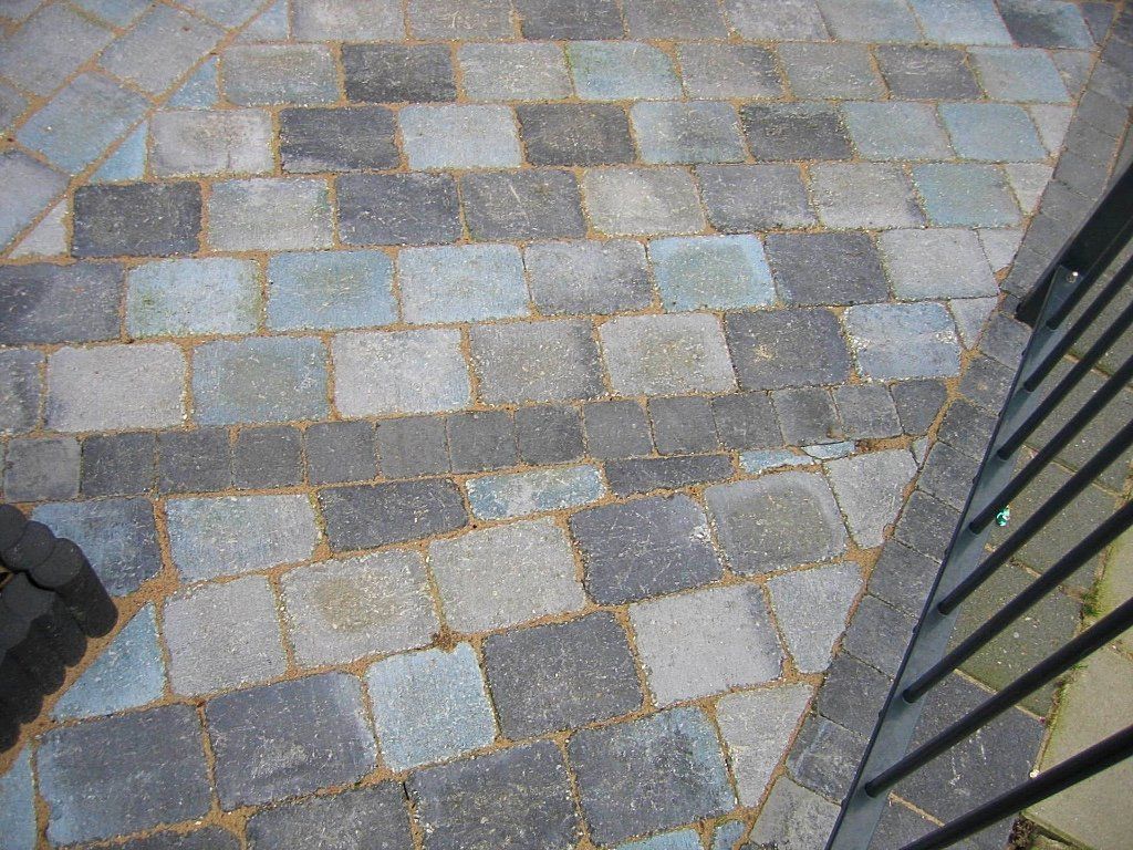 Terras van bakstenen met een dambordpatroon in blauw en grijs.