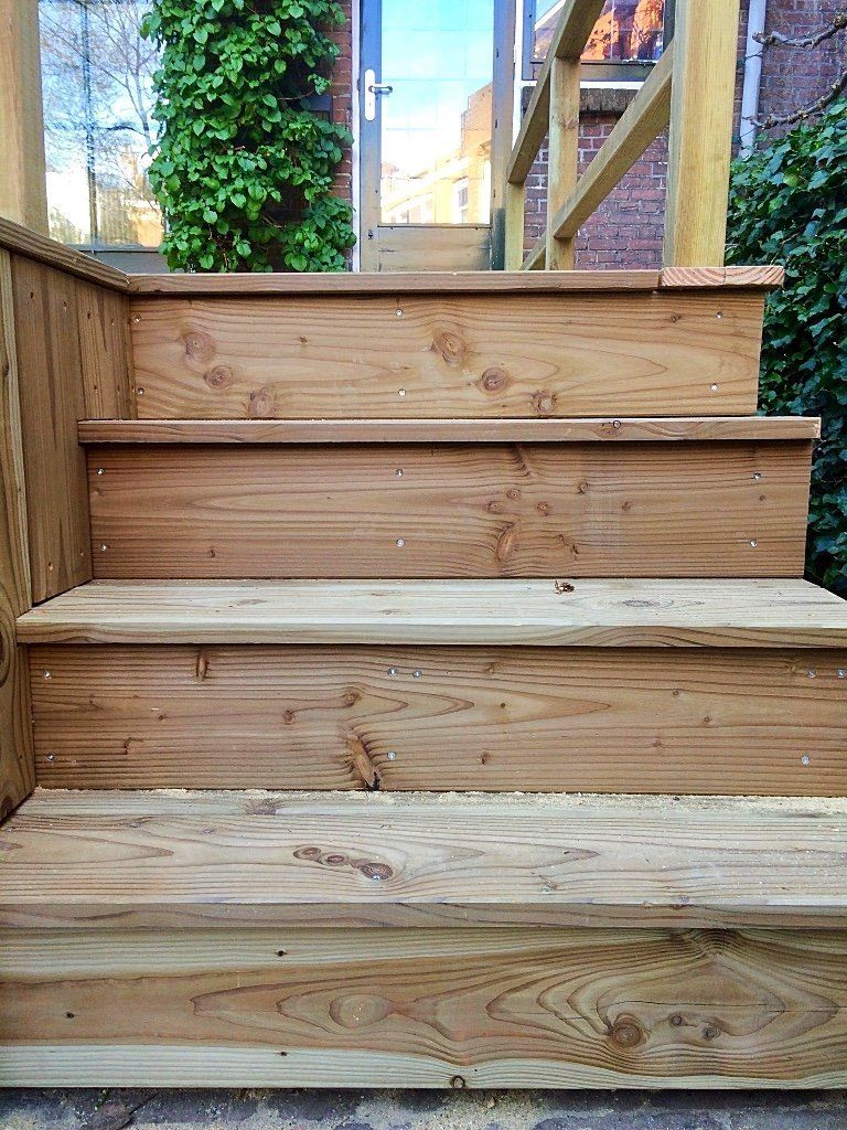 Houten buitentrap die naar een deur leidt.