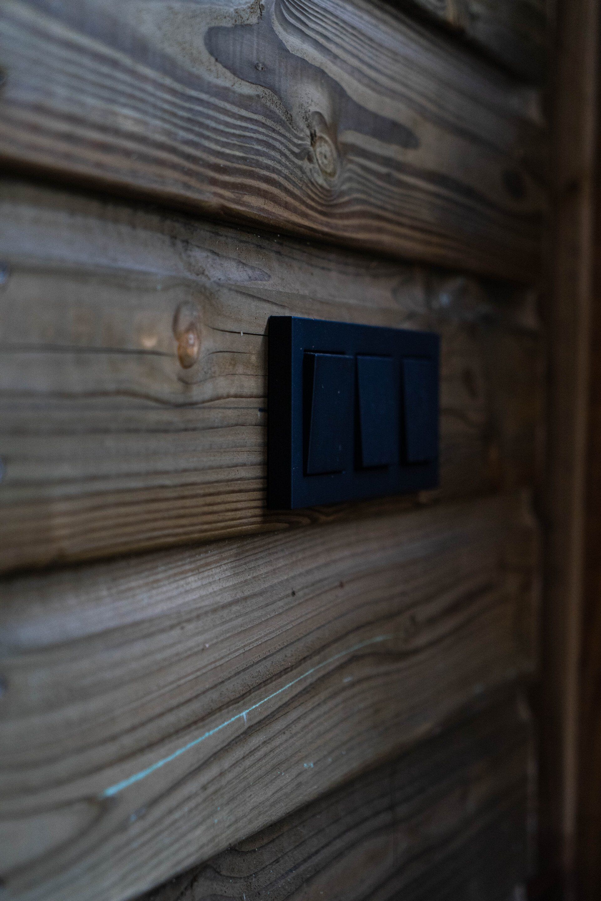 Zwarte lichtschakelaars op een houten muur.