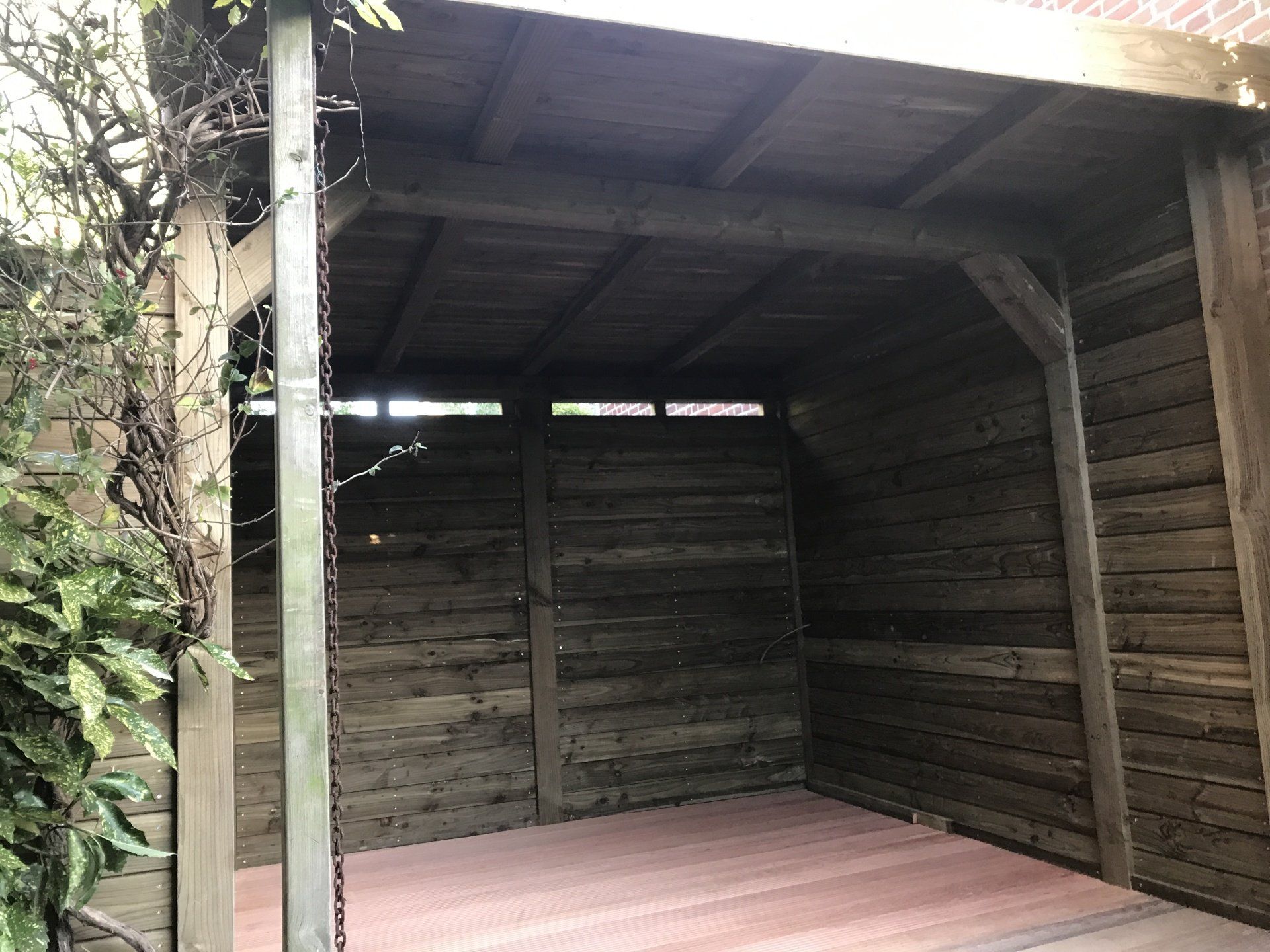 Houten schuur met een rode tegelvloer. Donkerhouten wanden en dak.