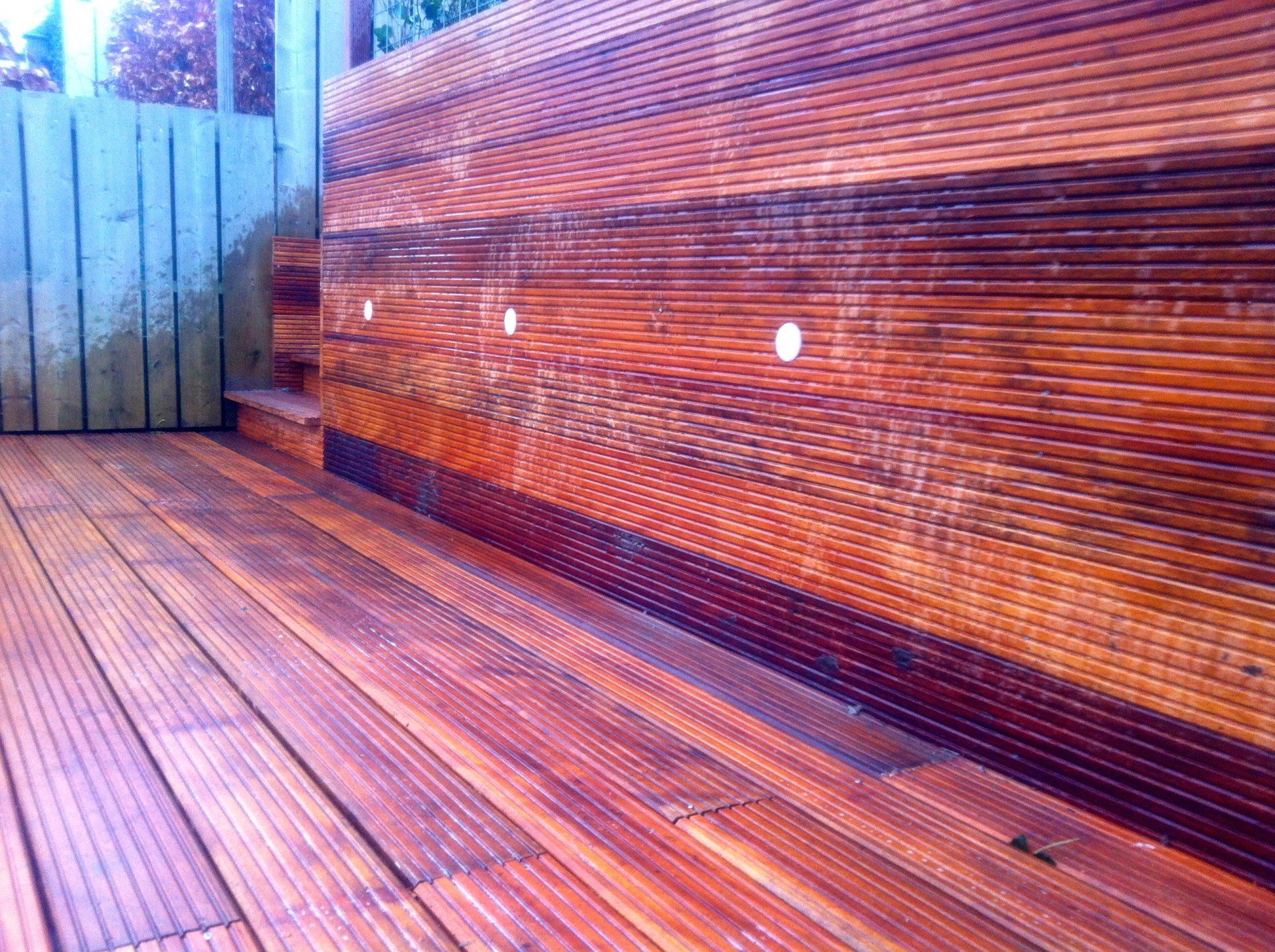 Houten terras met ingebouwde verlichting en trap, badend in warm licht.