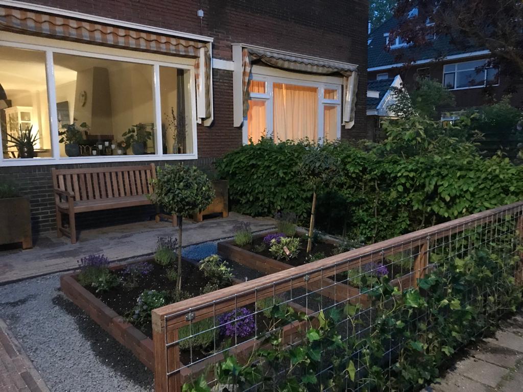 Een bakstenen huis met een voortuin, een houten bankje en een grindpad.