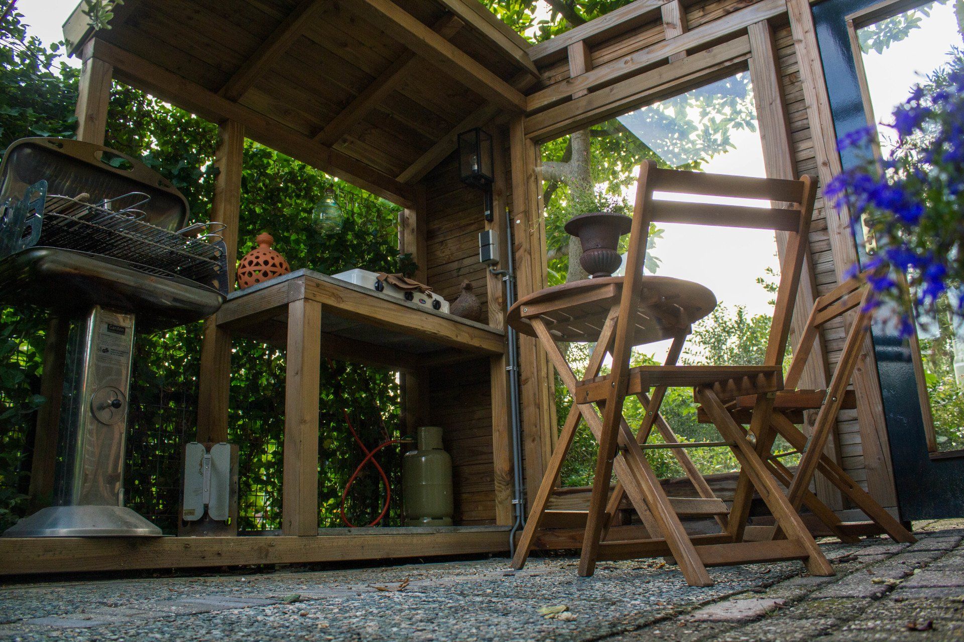 Houten barbecueplek voor buiten met een grill, tafel, stoelen en planken.