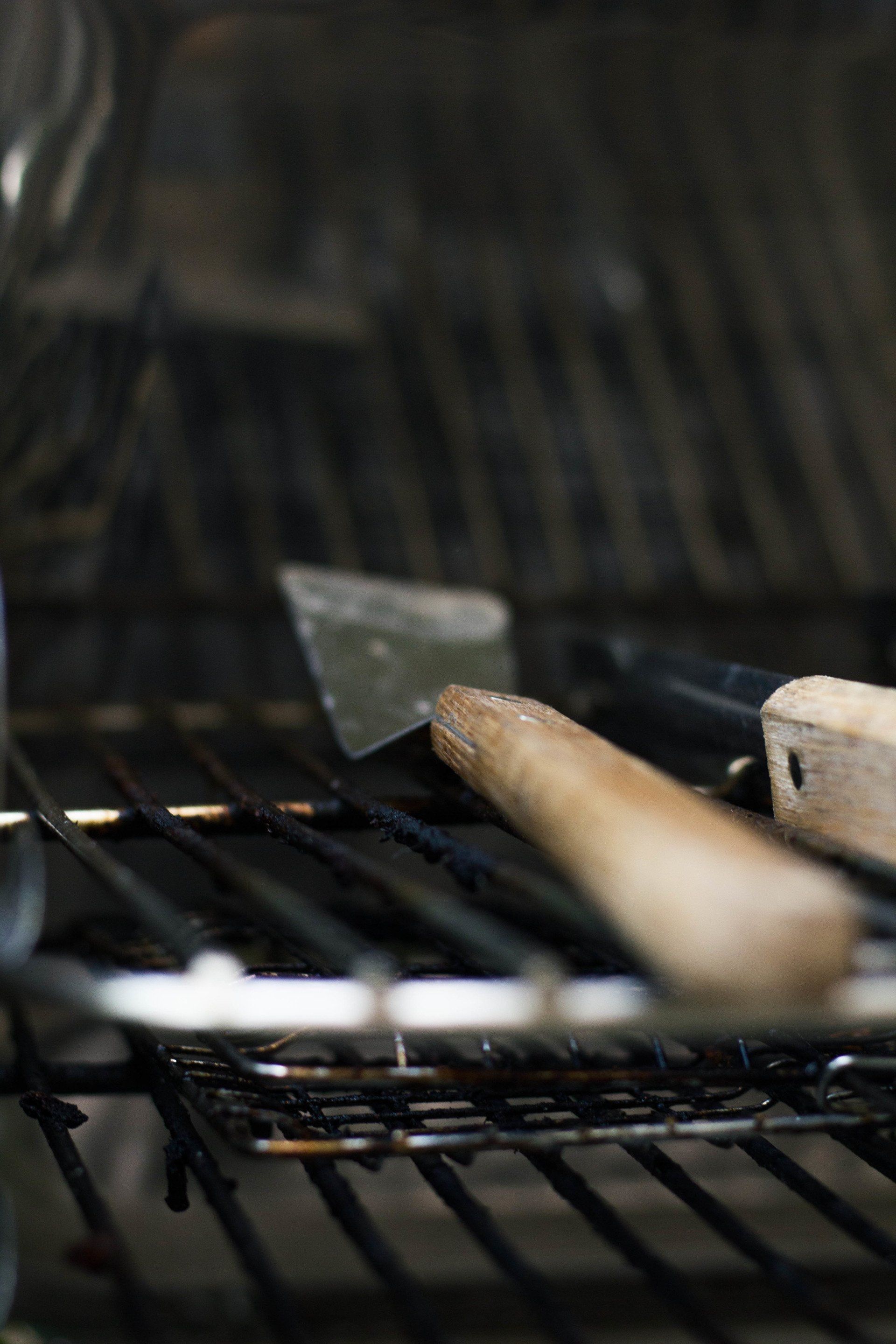 De binnenkant van de grill met een spatel en gereedschap met houten handvatten die op het rooster rusten.