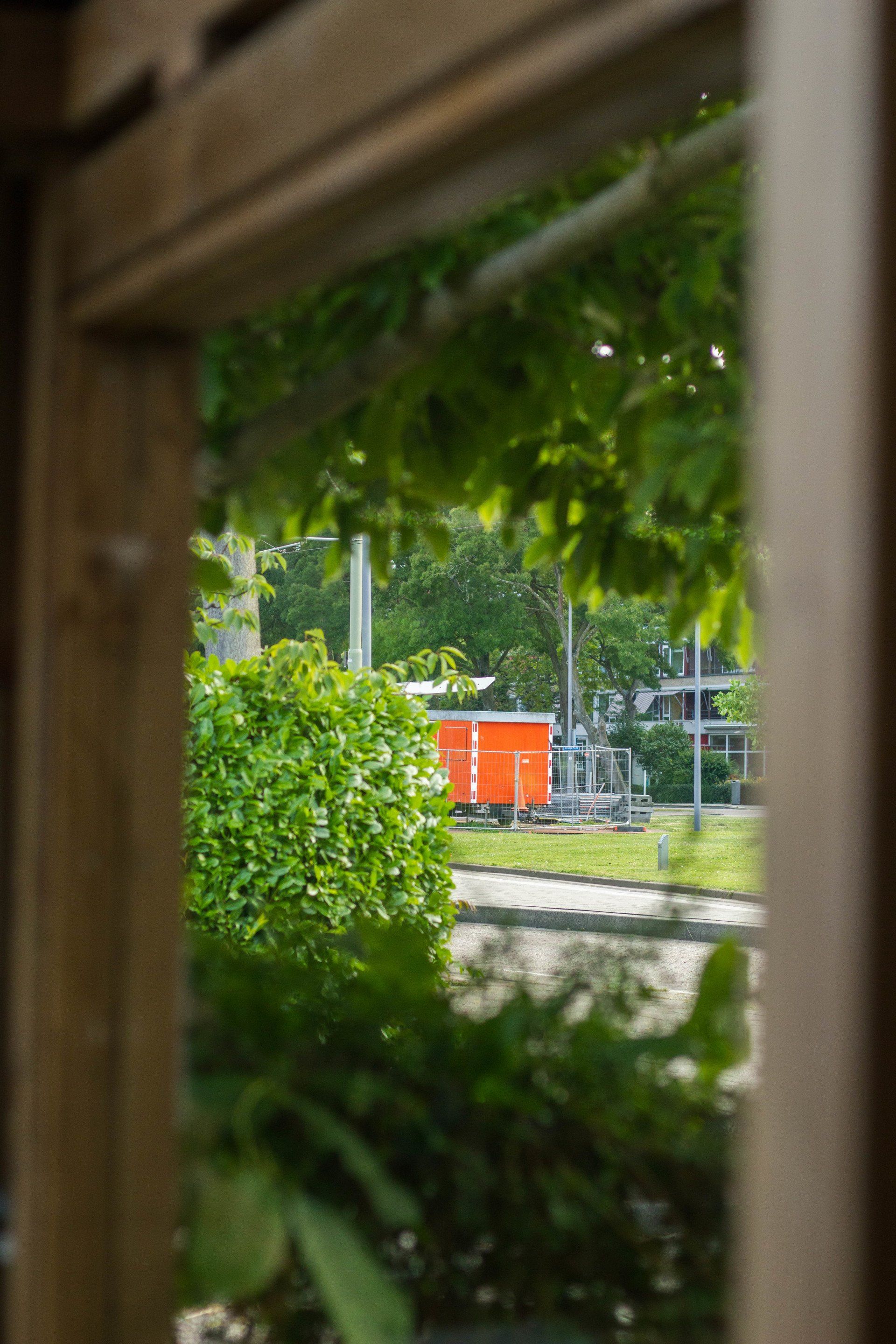 Oranje schuur, omgeven door groen en een houten constructie.
