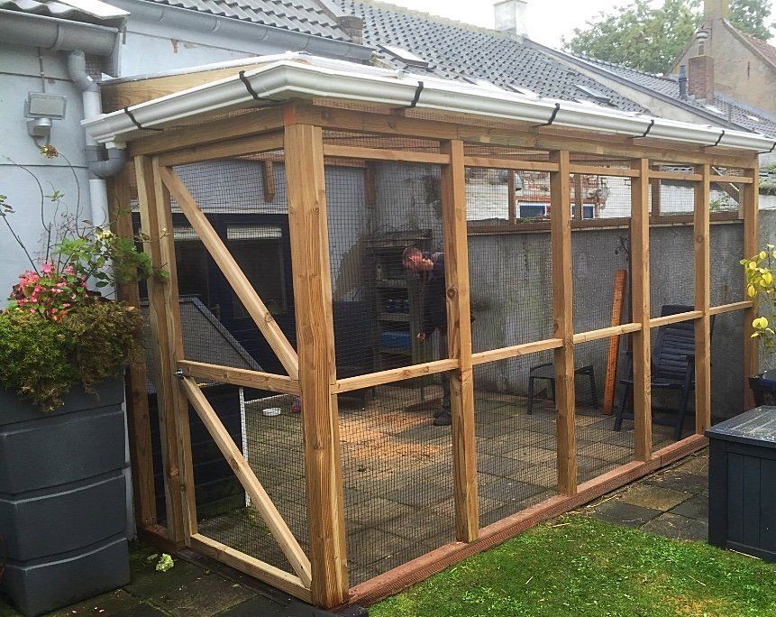 Houten kattenren in de tuin met een dak en gaaswanden.