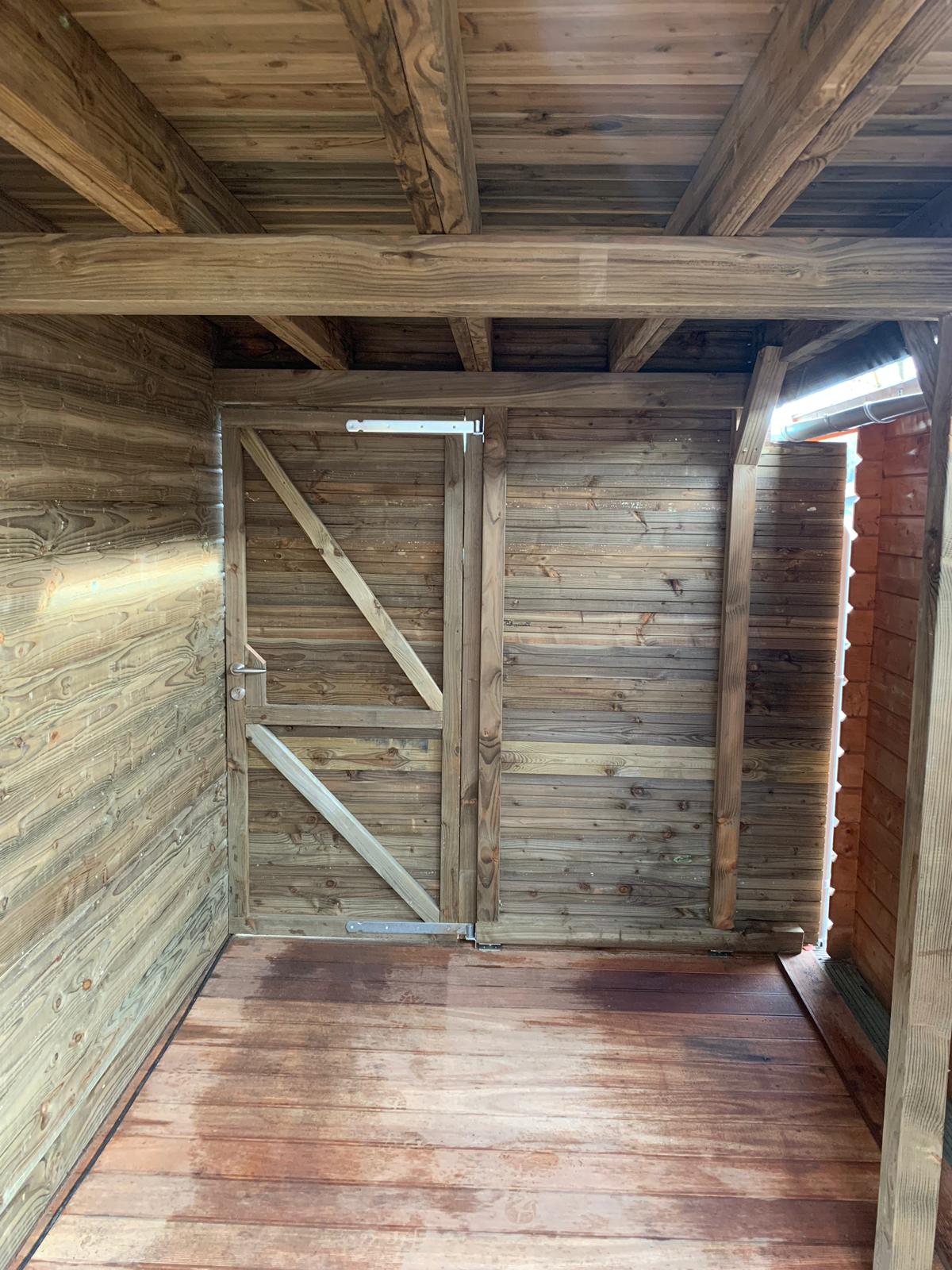 Interieur van een houten schuur met deur en wanden van planken.
