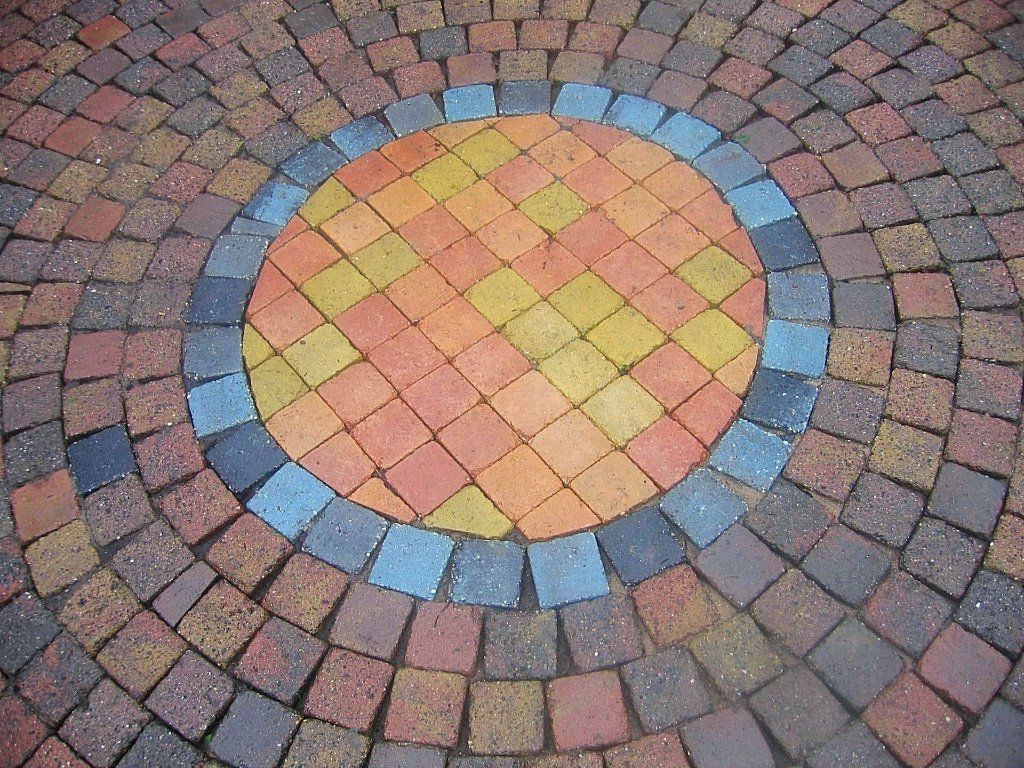 Rond terrasontwerp van bakstenen met kleurrijke concentrische ringen.