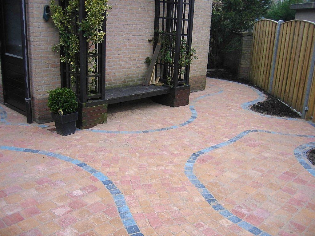 Een stenen terras met een gebogen blauwe rand die naar een bankje en een hek leidt.