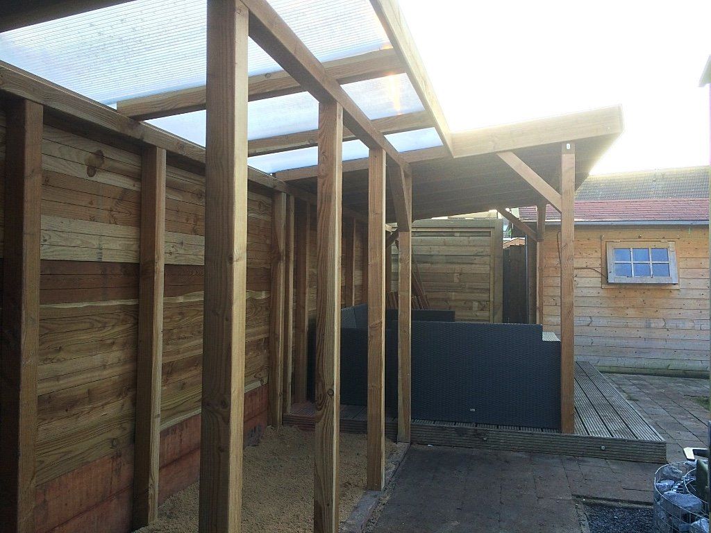 Houten constructie met een doorschijnend dak, aan één zijde open.