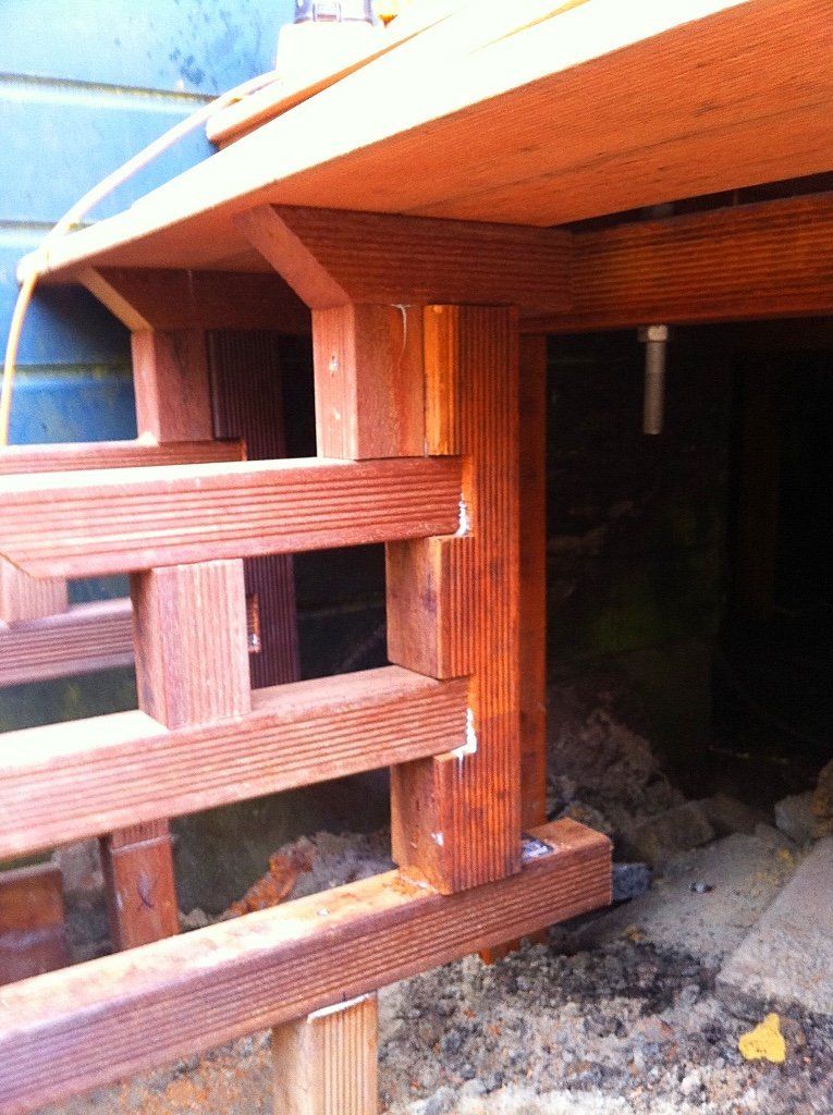 Houten terrasconstructie, met zichtbare steunpalen en reling in natuurlijk licht.