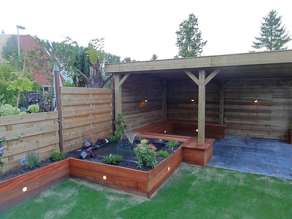 Houten buitenconstructie met verhoogd tuinbed, gazon en inbouwverlichting.