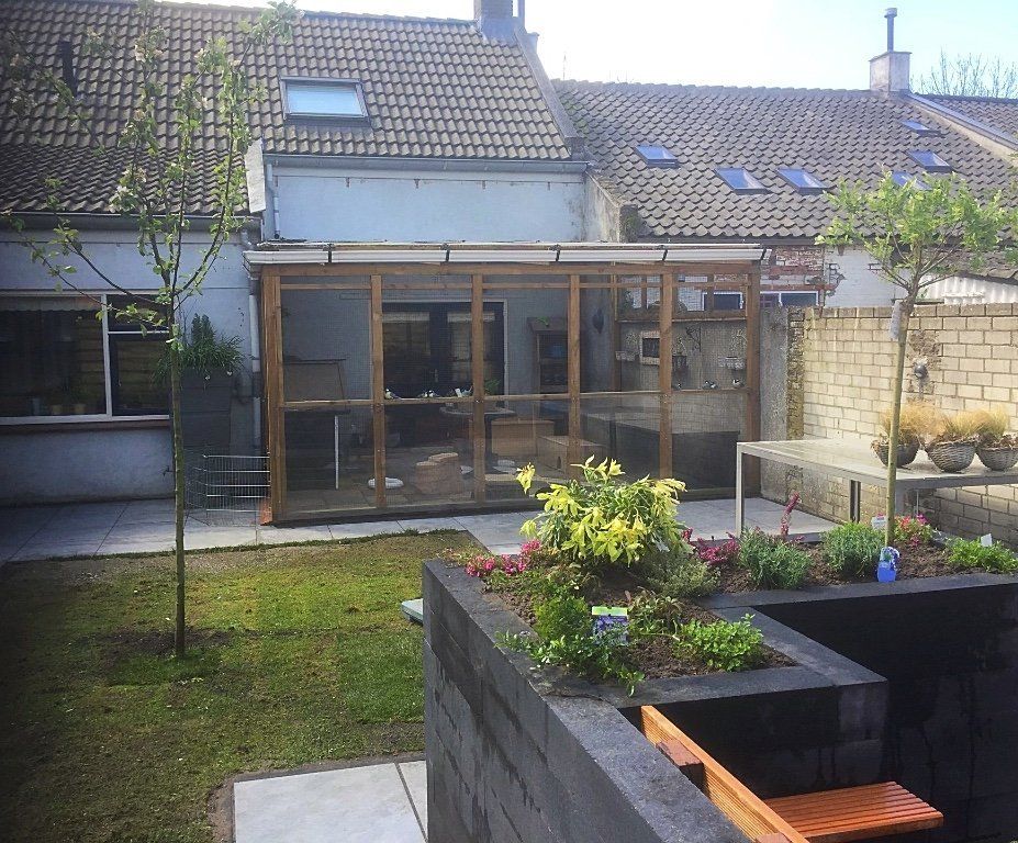 Terras in de achtertuin met houten afscheiding, tuin, gras en bakstenen muur. Zonnige dag.