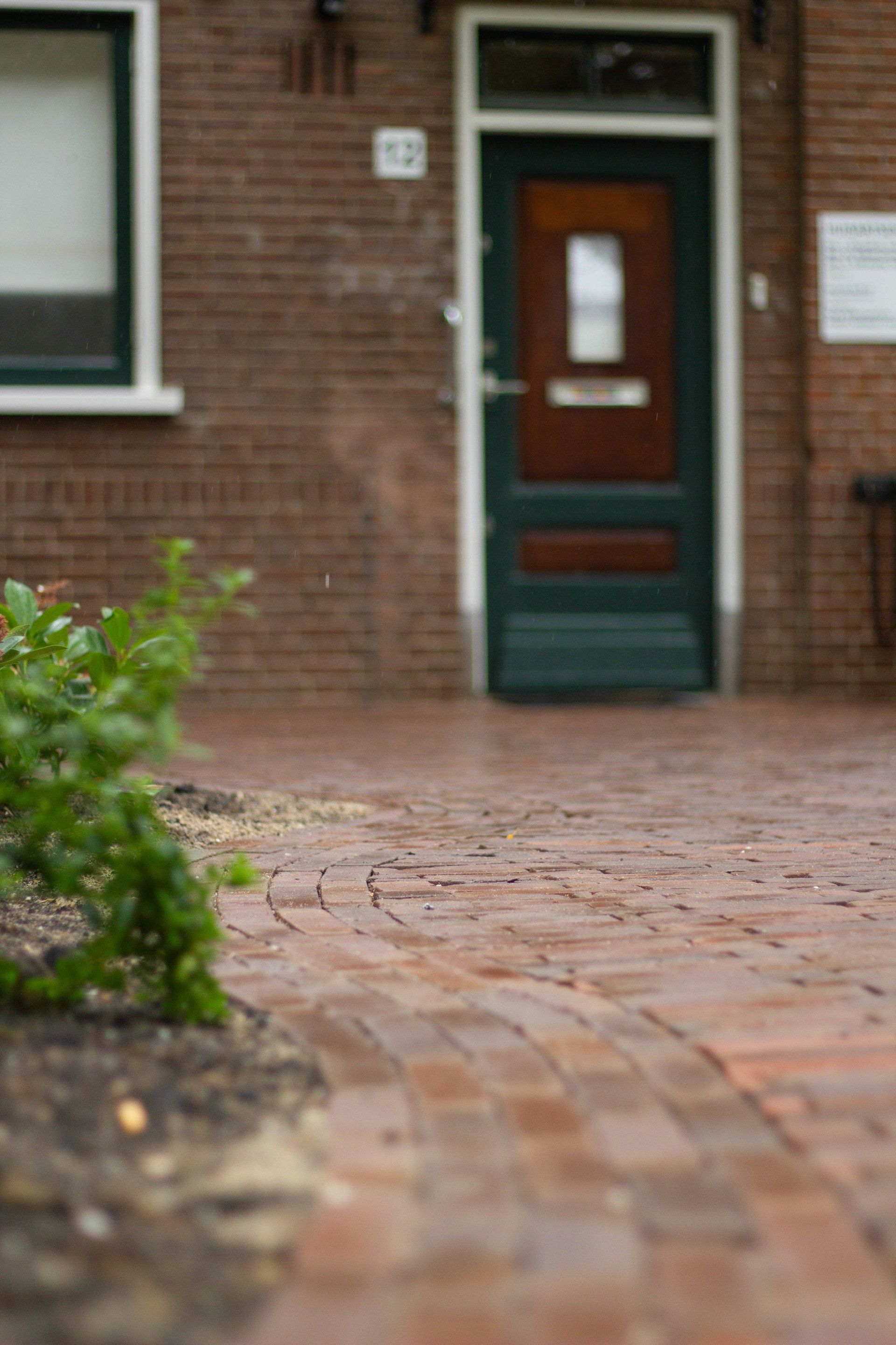 Een stenen pad leidt naar een stenen gebouw met een groene deur.