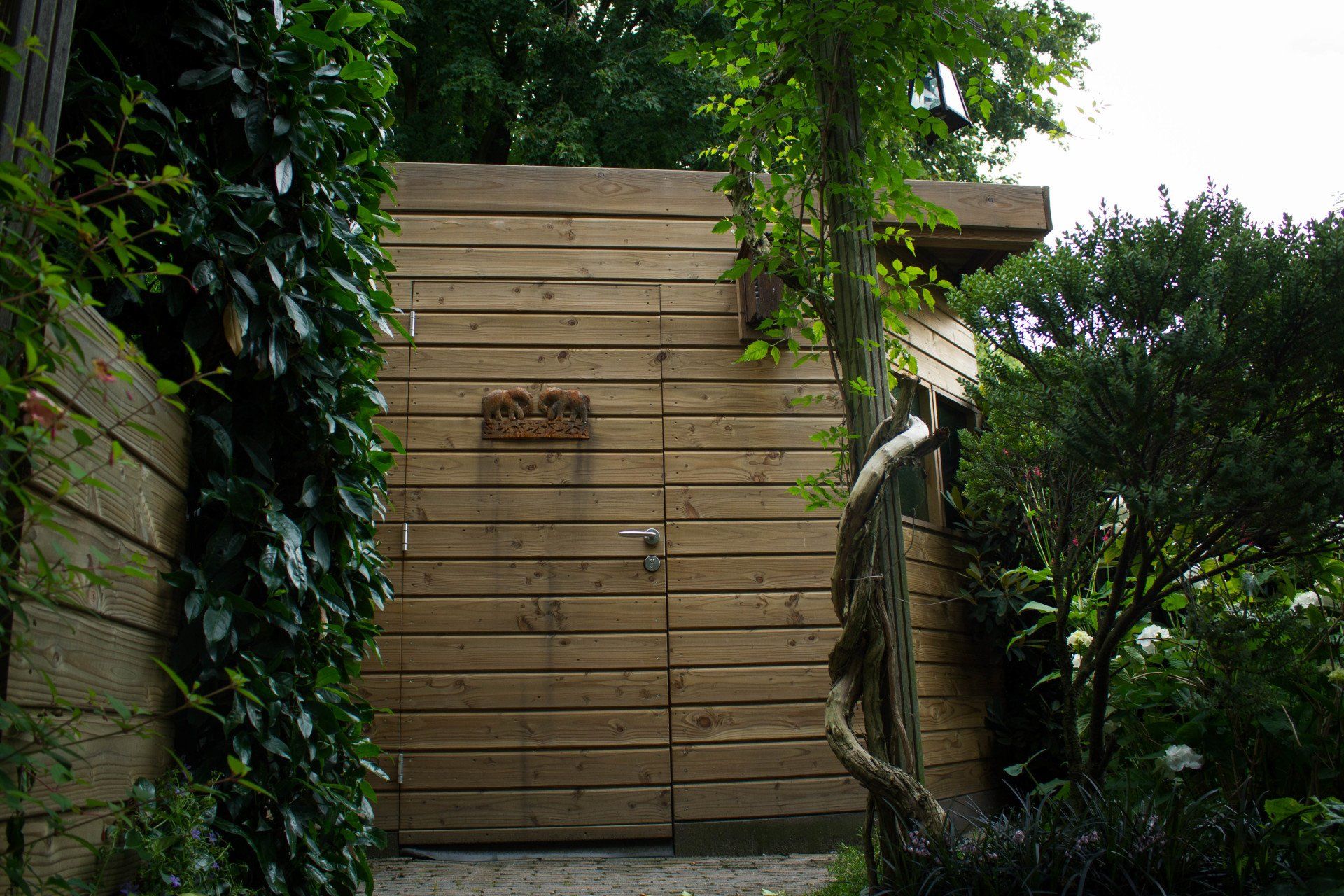 Houten poort in een weelderige, groene tuin.