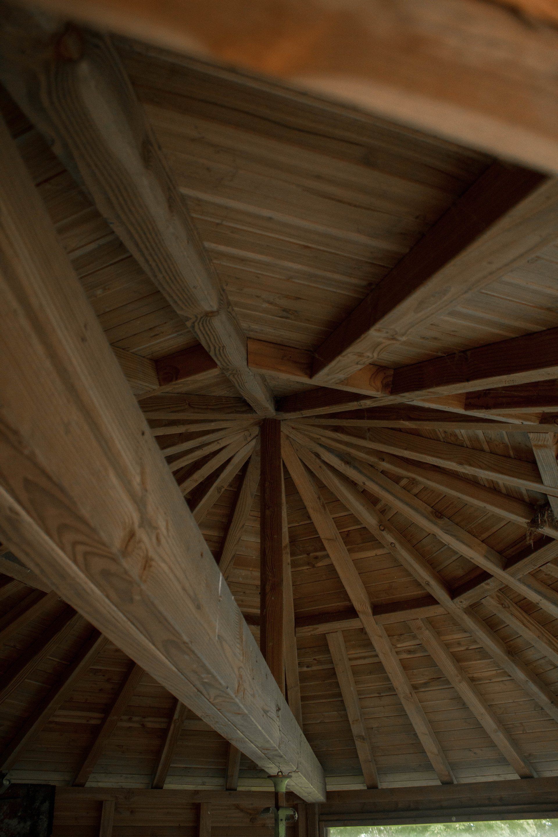 Houten prieelplafond met radiale balken die in een centraal punt samenkomen.