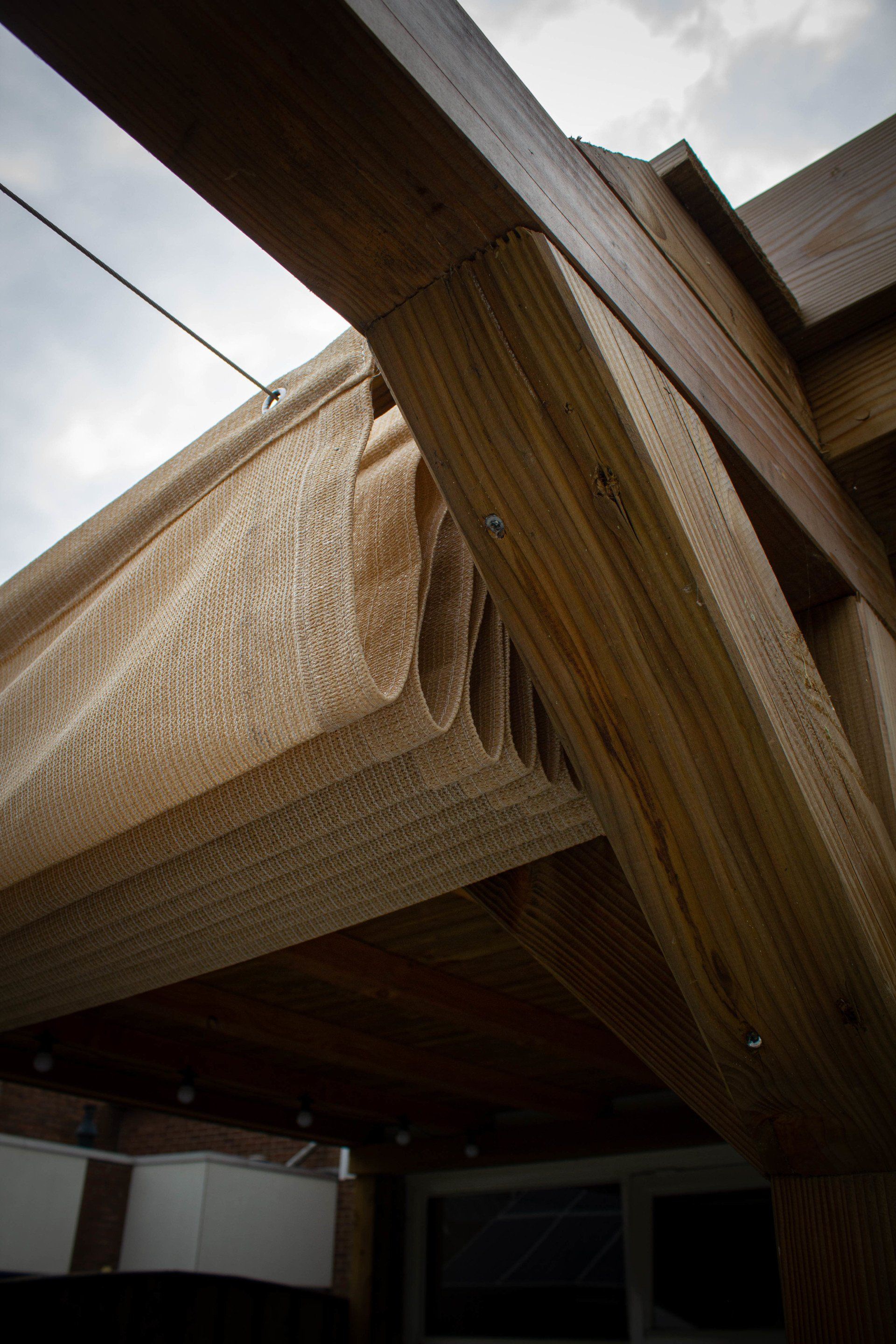 Houten architectonische balken, gedetailleerd weergegeven, onder een bewolkte hemel.