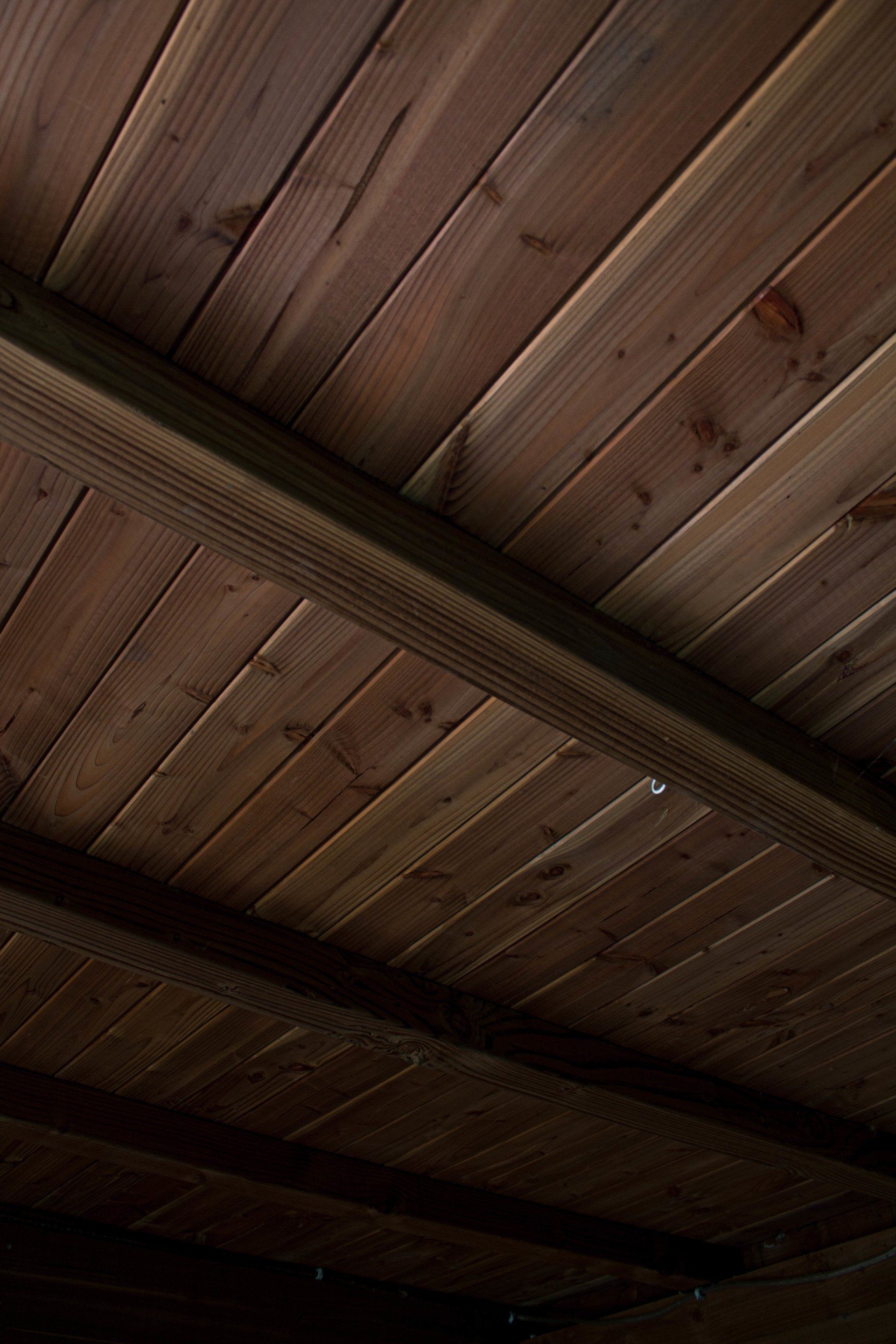Houten plafond met donkerbruine planken die diagonaal zijn geplaatst.