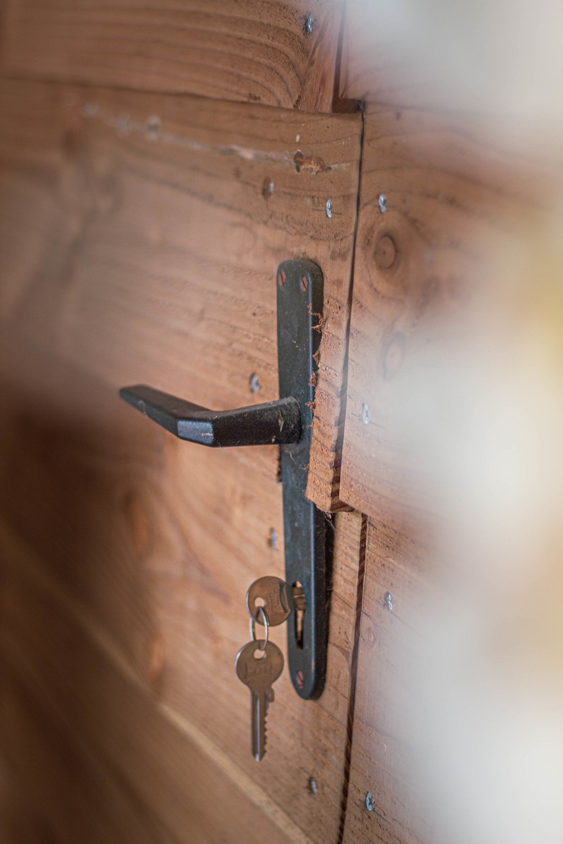 Houten deur met zwarte handgreep en sleutels in het slot.