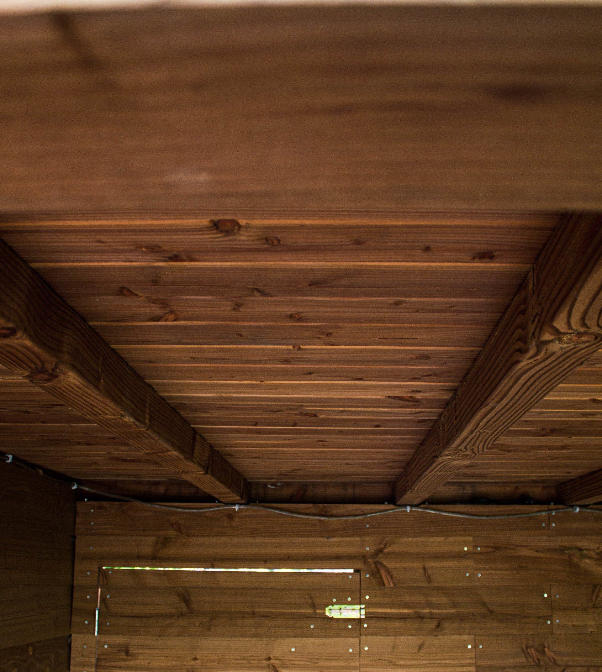 Houten plafond en muur met zichtbare balken en planken. Bruine tinten, interieurfoto.